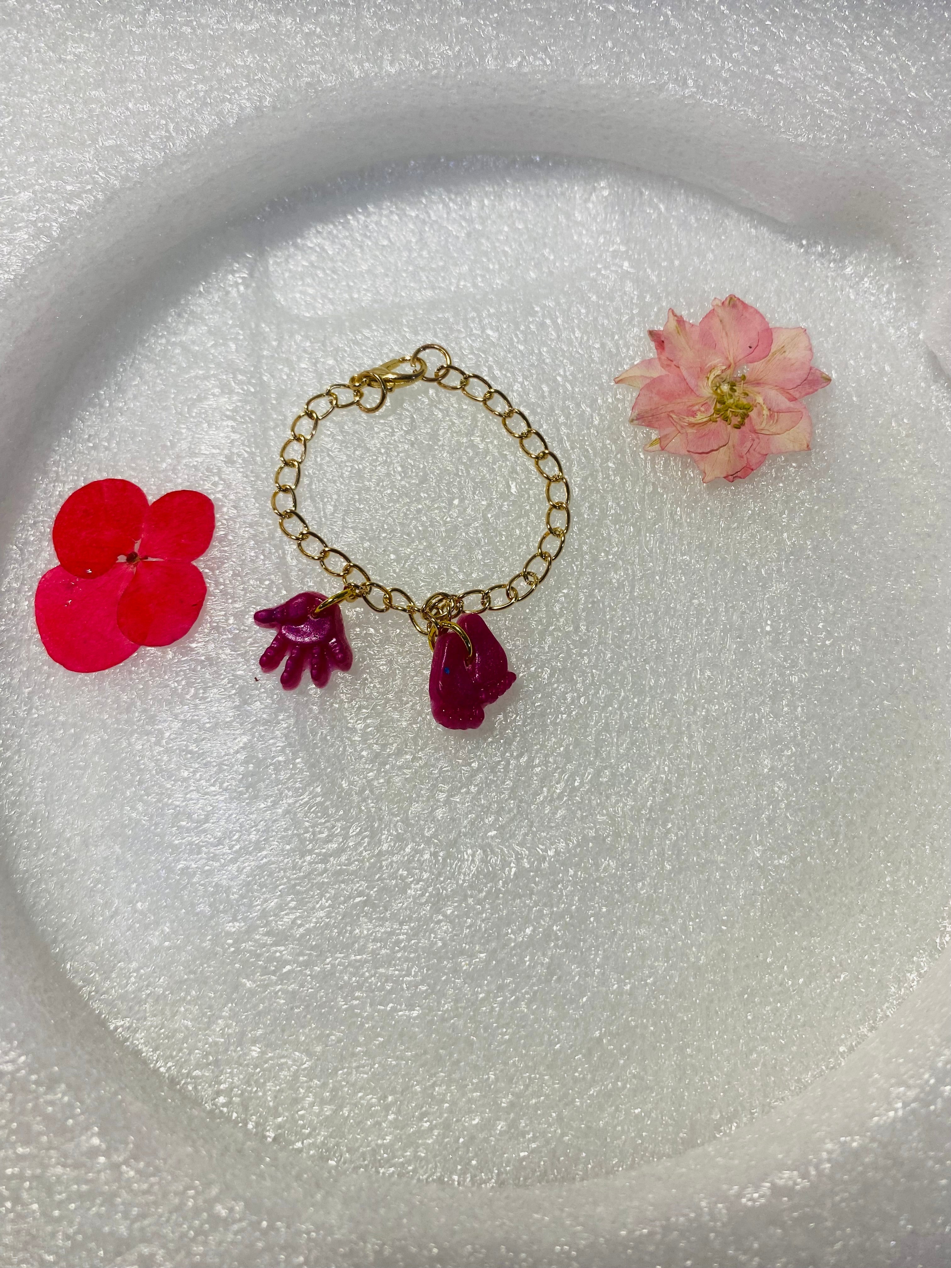 Pulsera Artesanal con dijes de manitas y pies de bebé.